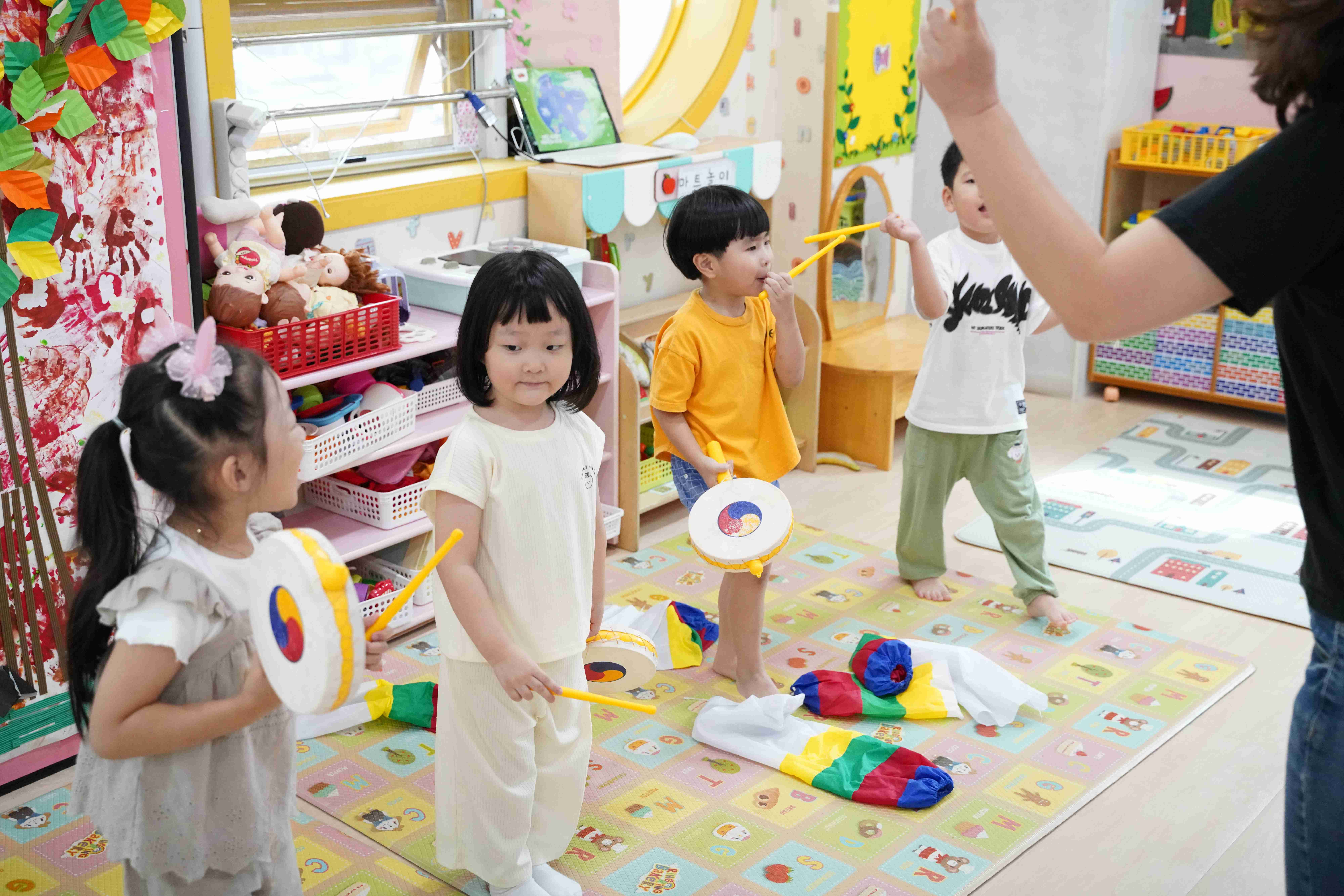 아이들이 색색의 낙하산을 들고 신나게 놀이하는 모습