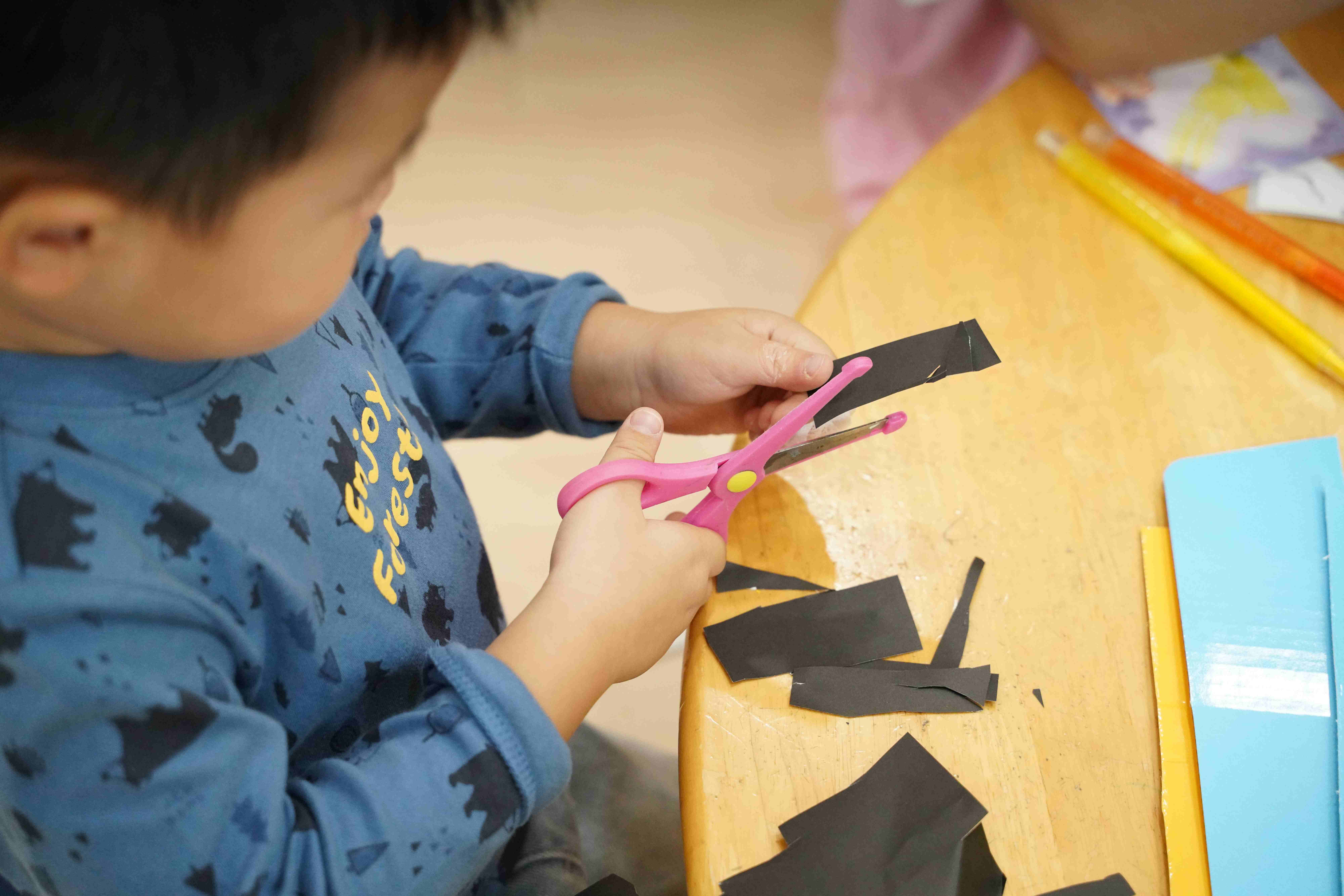 아이가 가위로 종이를 자르며 소근육을 발달시키는 모습
